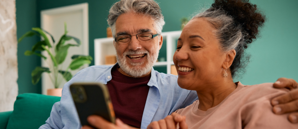 Smiling couple in living room looking at cell phone